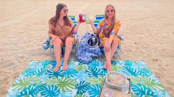 Two Women Enjoying AVO's Cocktail Quarts to Go at the Beach